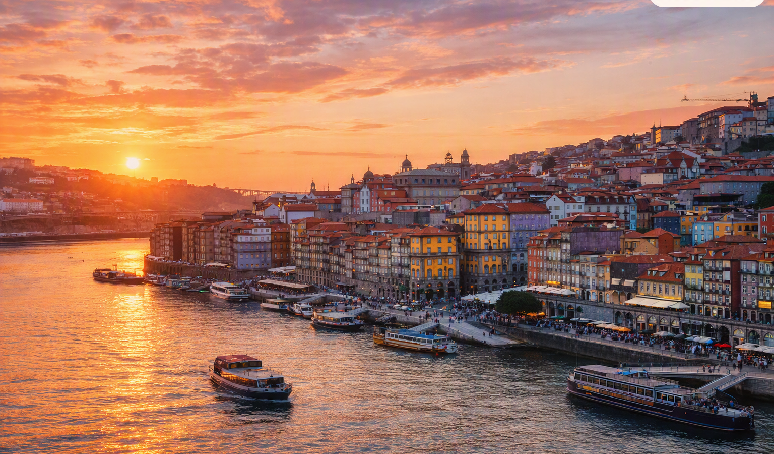 a luminous sunset view of the Ribeira district along the Douro River, with the Dom Luís I Bridge arching gracefully across the water